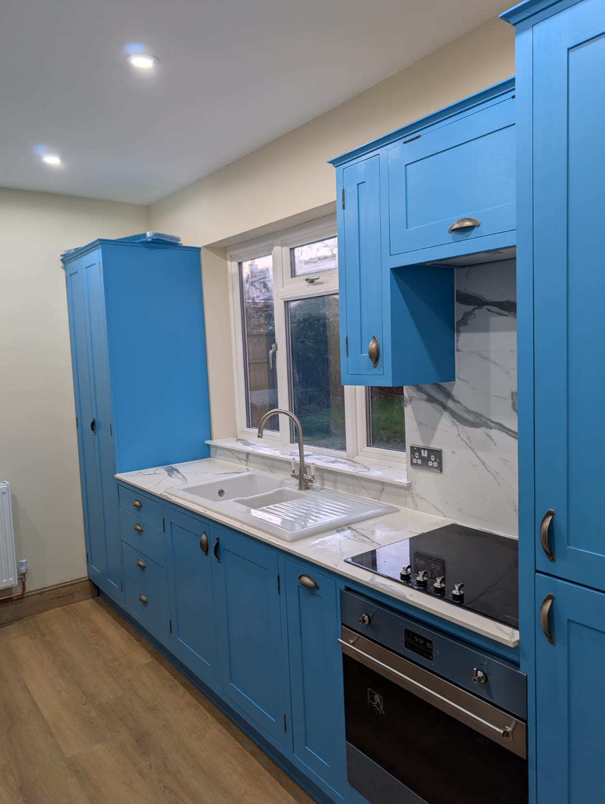 Blue handmade kitchen cabinetry with sink, oven and worktops
